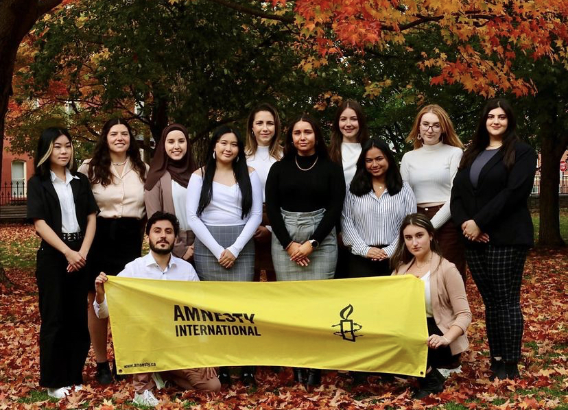 Amnesty members holding a banner with autumn leaves in the background.