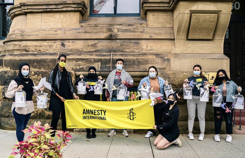 Amnesty members holding a banner and containers of letters.